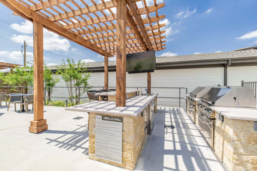 the outdoor patio has a grill and a table with a tv