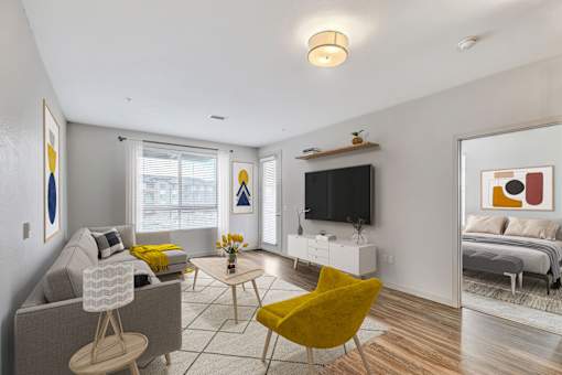 A living room with a grey couch, yellow chair, and a television.