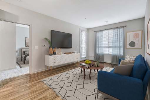 A living room with a blue couch and a black and white rug.