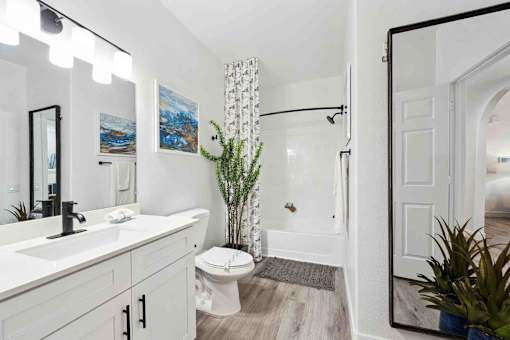 A white bathroom with a toilet, sink, and mirror.