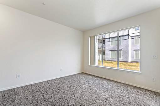 Empty room with a large window overlooking a building.