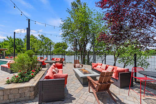 A patio with red cushions and wooden chairs overlooks a body of water.