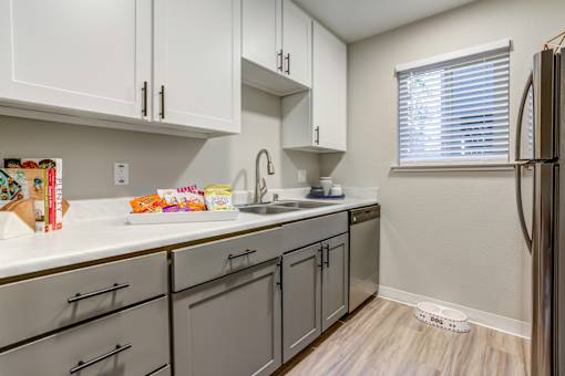 A kitchen with white cabinets and a refrigerator.