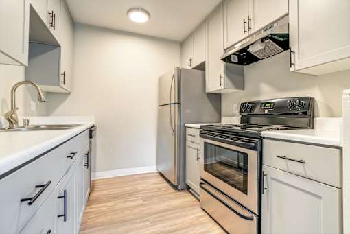 A kitchen with white cabinets and a black stove top oven.