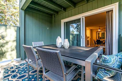 A table with chairs and vases on it outside a house.