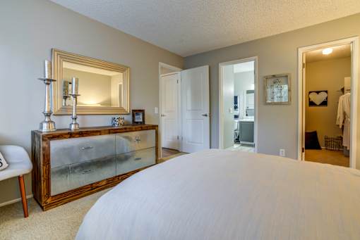 A bedroom with a large bed and a dresser with a mirror.