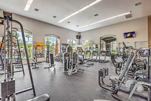 A gym with a variety of equipment including treadmills, weights, and exercise machines.
