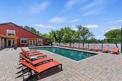 A pool area with red sun loungers and a red building.
