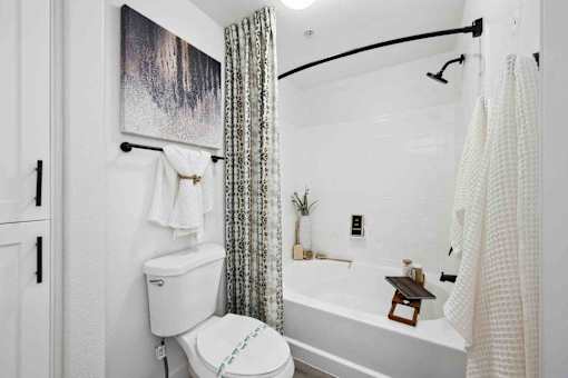 A white toilet sits next to a white bathtub in a bathroom.