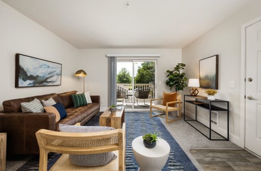 Living room with brown leather sofa and patio door at Canyon Creek Apartments, Wilsonville, OR 97070