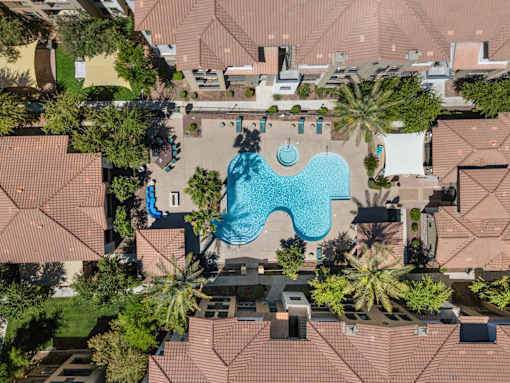 An aerial view of a swimming pool surrounded by houses and trees.
