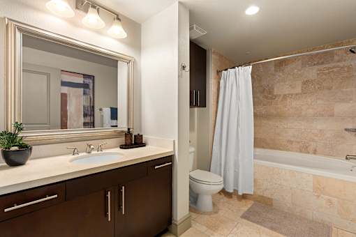 A bathroom with a sink, mirror, toilet and bathtub.