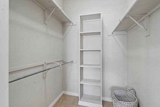 A white closet with shelves and a basket on the floor.