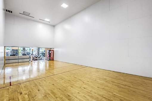 A large empty room with wooden flooring and white walls.