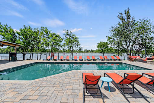 A pool area with red chairs and a clear blue sky.