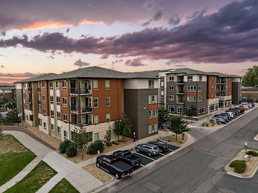 A parking lot in front of a building with cars parked.