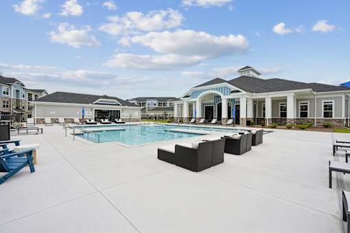A large outdoor swimming pool area with sun loungers and a building in the background.