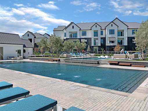 A large swimming pool with lounge chairs in front of a building.