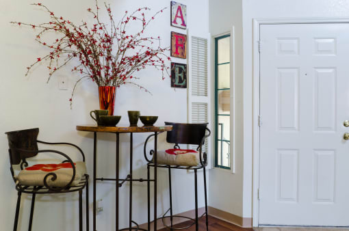 a dining room with two chairs and a table and a vase of flowers