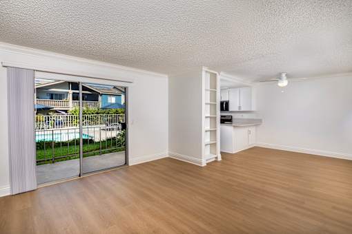 A spacious living room with a sliding glass door leading to a balcony.