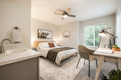 Bedroom with desk workspace and ceiling fan at Canyon Creek Apartments, Wilsonville, Oregon