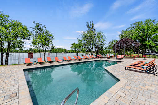 A pool surrounded by trees and chairs.