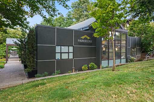 A building with the words "PARKRIDGE" on it is surrounded by trees and grass.