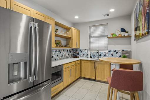 A kitchen with a stainless steel refrigerator and wooden cabinets.