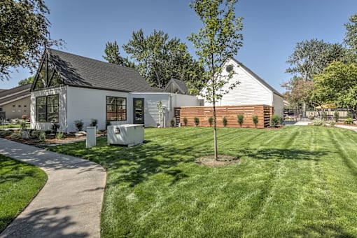 A white house with a black roof and a tree in front.