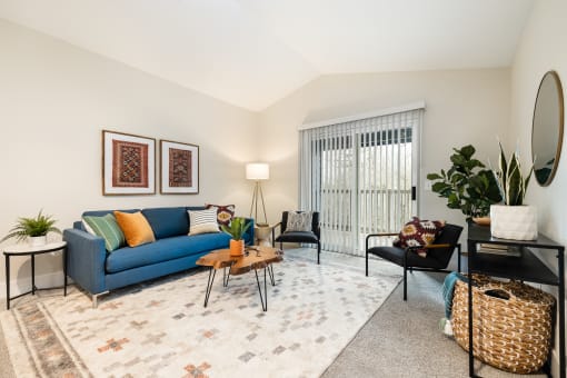 Living room with blue sofa and accent chairs at Canyon Creek Apartments, Wilsonville