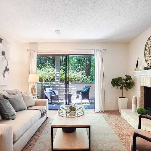 A living room with a white couch, a coffee table, and a fireplace.