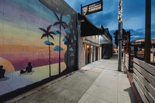 a mural on the side of a building on a sidewalk