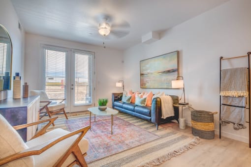 a living room with a blue couch and white chairs