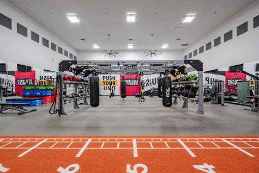 A gym with orange floor markings and a variety of equipment.