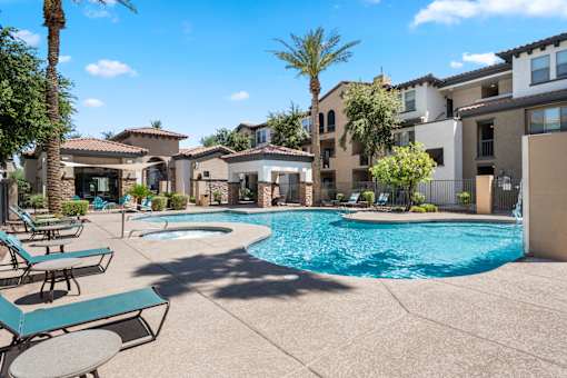 A pool surrounded by lounge chairs and palm trees.