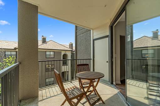A balcony with a table and chairs overlooks a building.