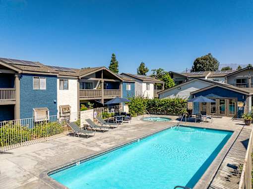 A swimming pool surrounded by lounge chairs and townhomes.