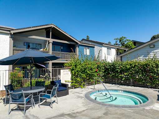 A hot tub with a table and chairs and umbrella.