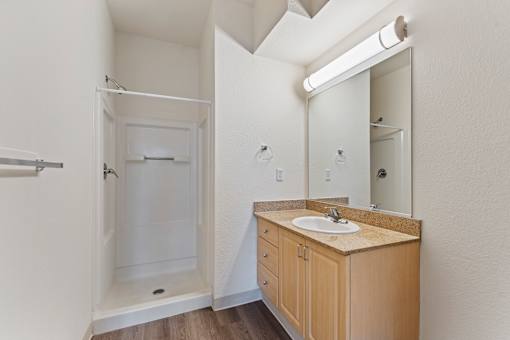 A bathroom with a sink, mirror, and shower.