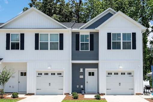 A two-story house with white and grey exterior and two garages.