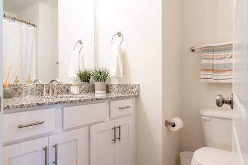 A white bathroom with a toilet, sink, and mirror.