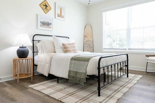 A bedroom with a bed, a lamp, a surfboard, and pictures on the wall.