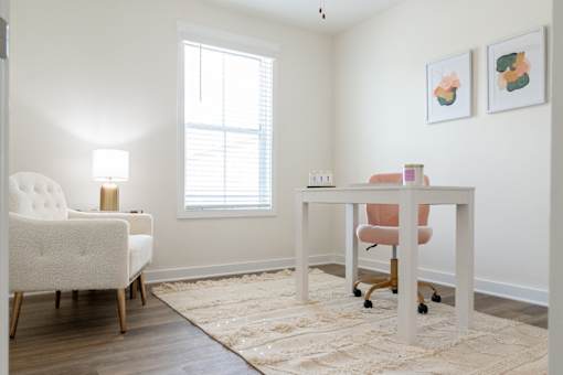 A white chair sits in front of a desk with a pink chair in front of it.