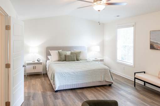 A bedroom with a bed, a bench, and a ceiling fan.
