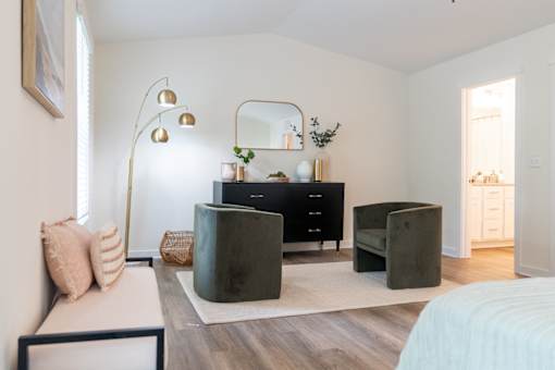 A modern bedroom with a large bed, a dresser, and a chair.