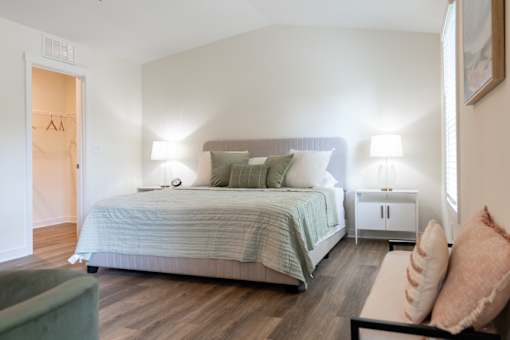 A bedroom with a bed, nightstand, and chair.
