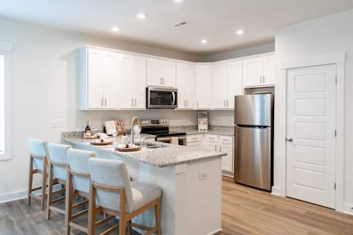 A kitchen with a refrigerator, microwave, oven, and sink.