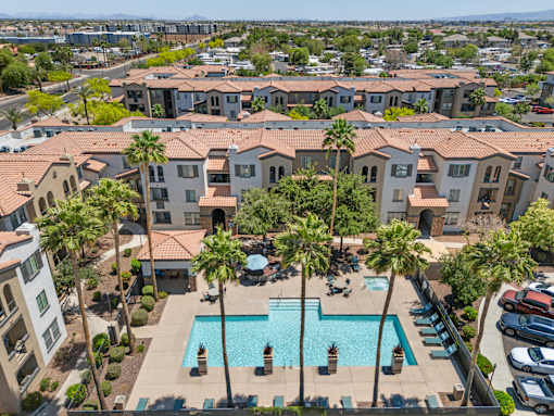 A swimming pool surrounded by palm trees and apartment buildings.