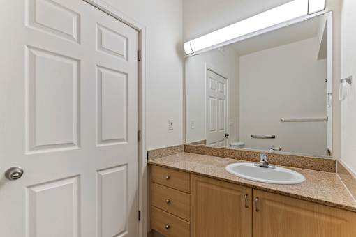 A bathroom with a white door, a sink, and a mirror.
