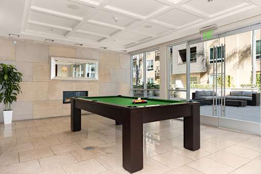 A pool table in a room with a mirror above it.